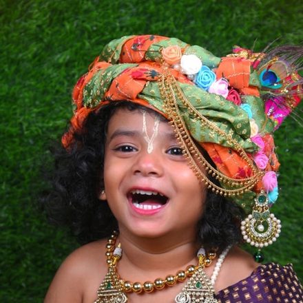 A smiling child dressed as Krishna